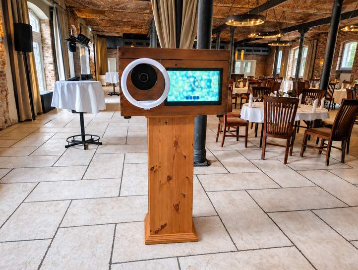 Fotobox im Holzdesign mit Kamera und Touchscreen in einer festlich eingerichteten Location.